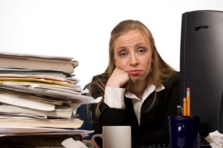 Fed up woman with pile of paper at desk